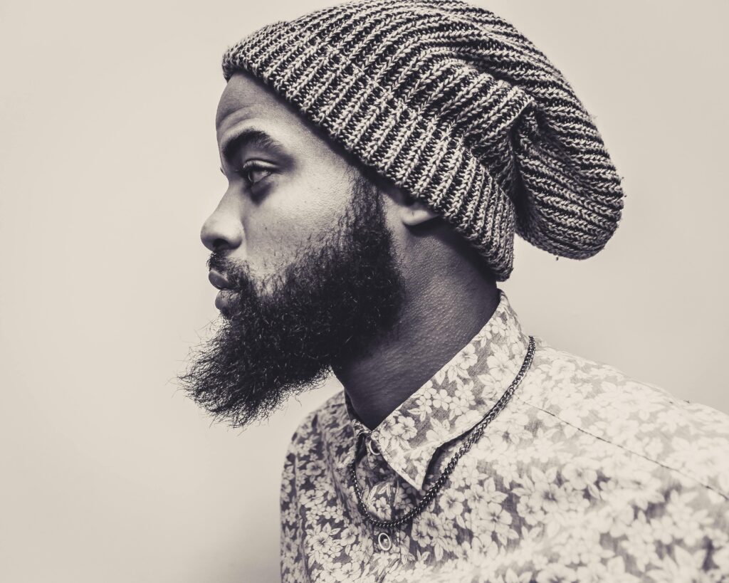 Profile photo of a bearded man in a knit hat and floral shirt, exuding modern style.